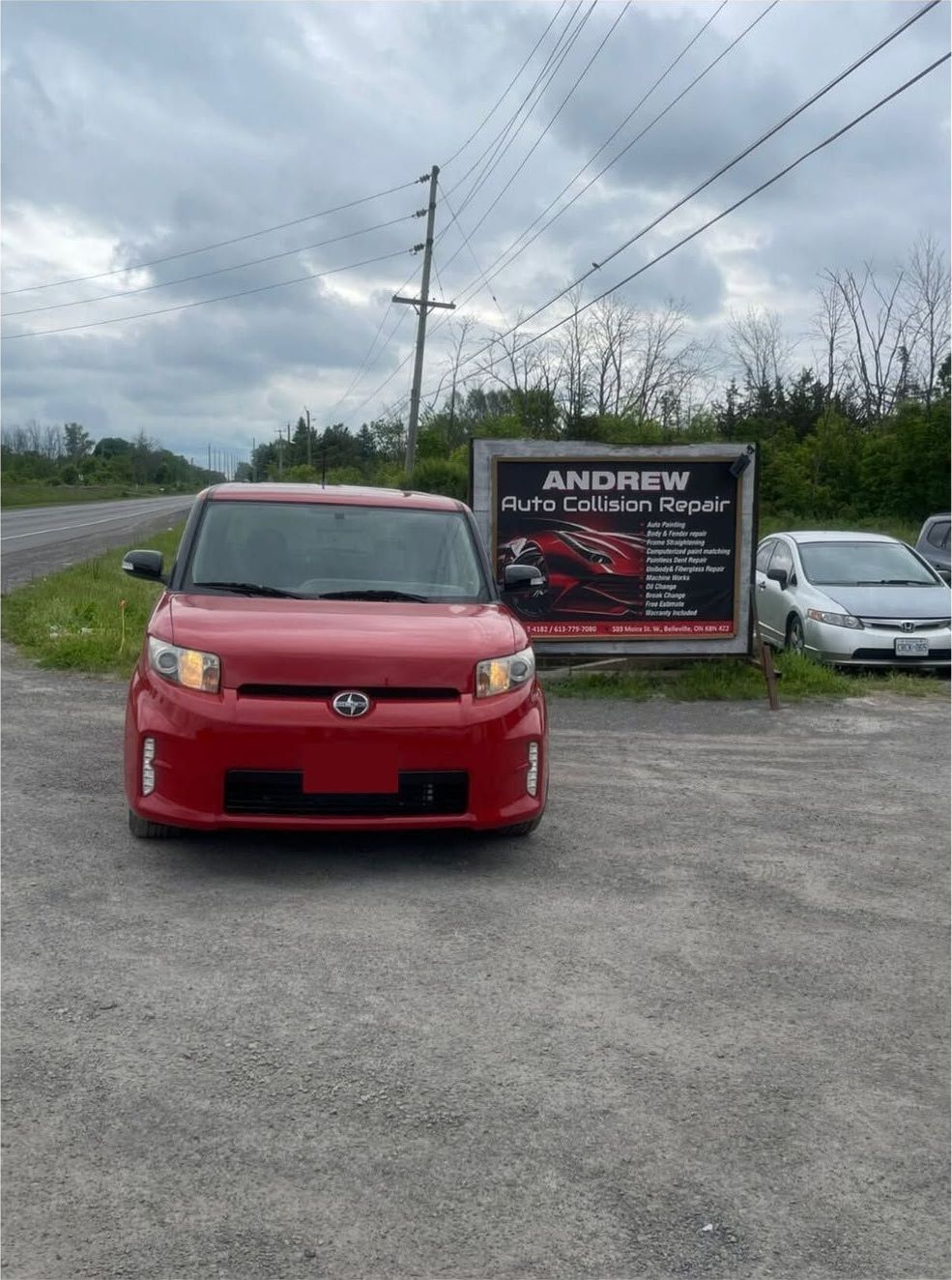 Repainted red Scion xB parked in front of the Andrew Auto Collision Repair sign on Moira Street West